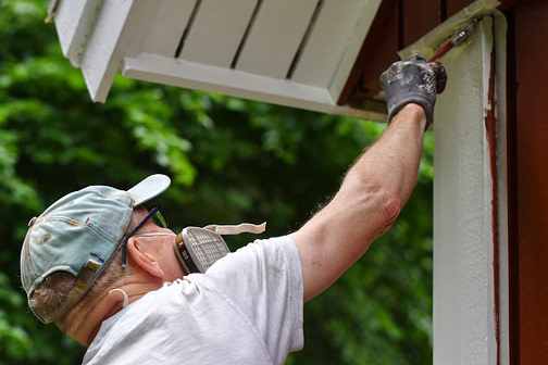 male painting the exterior of his house in ideal outdoor painting temperature